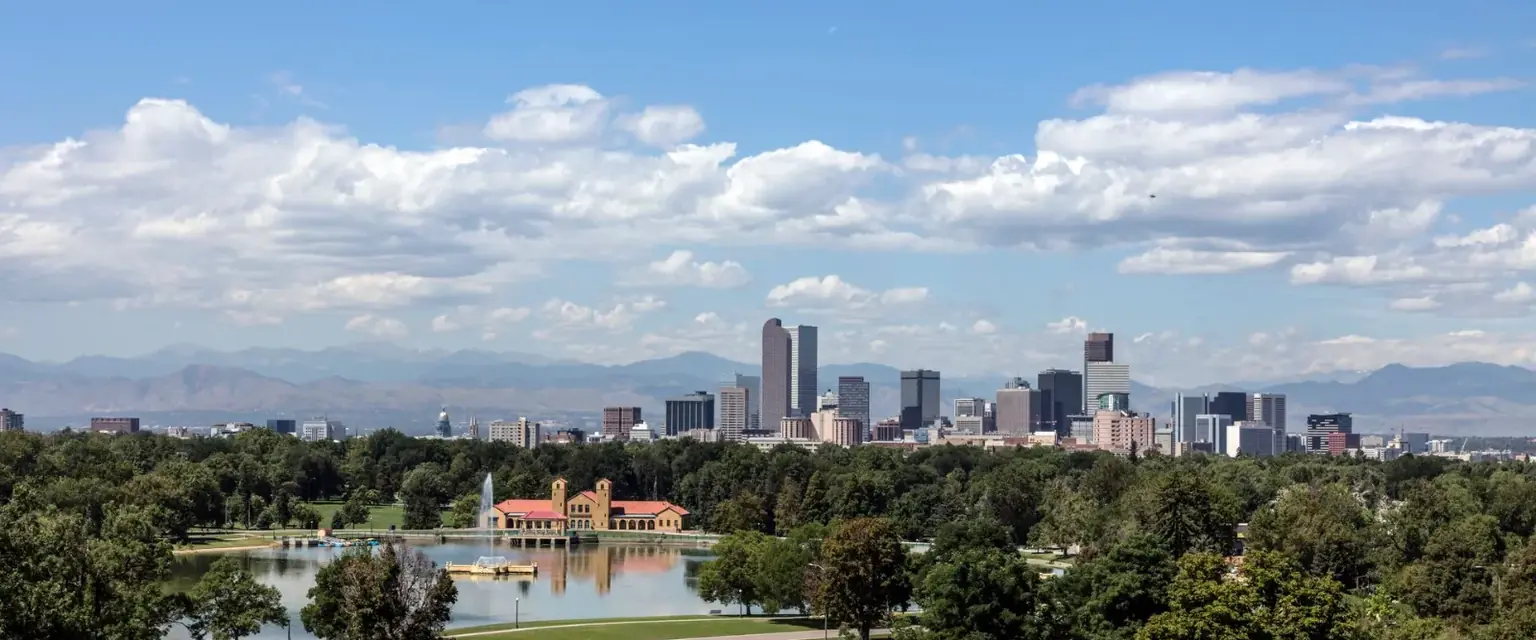 Photo: the Denver skyline across Ferril Lake in City Park, with the Front Range behind