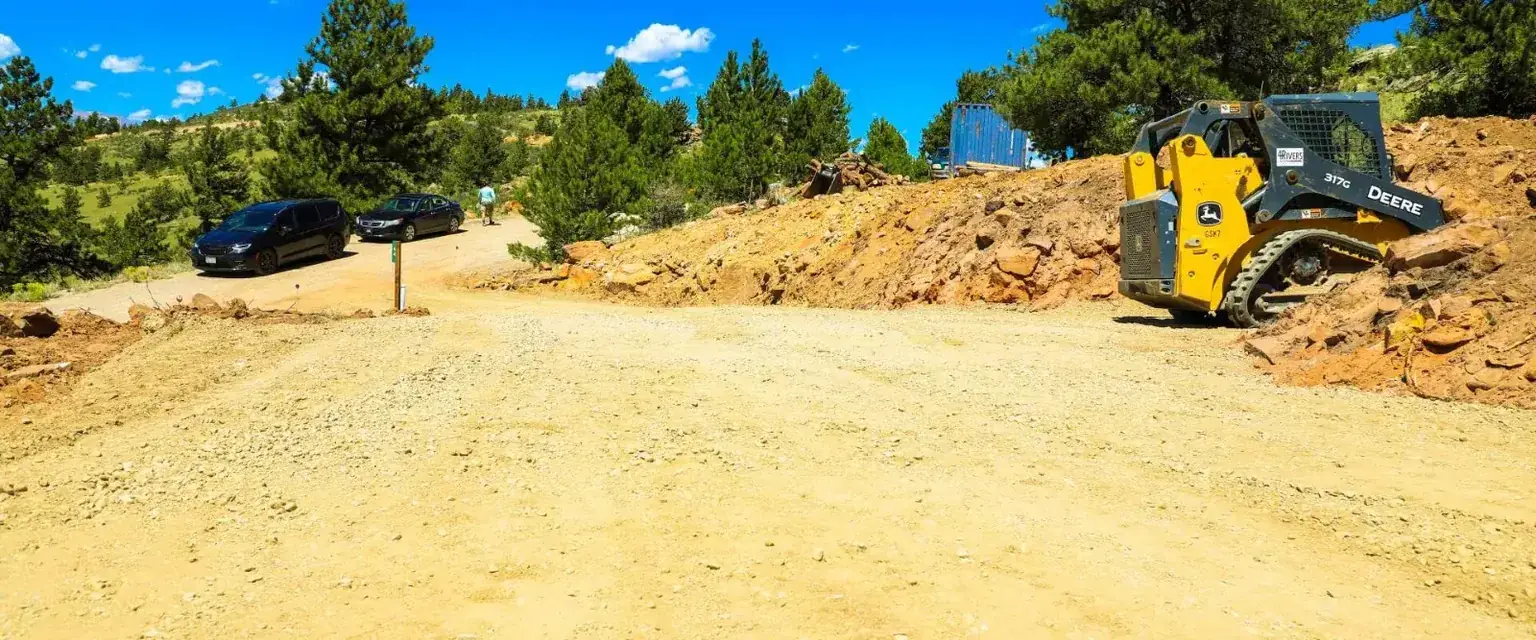 Photo: a freshly graded lot in Park County with an excavator at the tree line