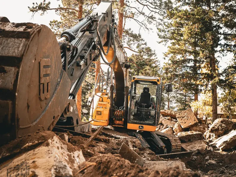 Photo: a Deere excavator opening a cut in red mountain soil