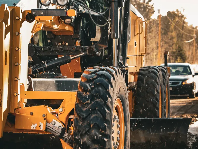 Photo: a Deere motor grader on a gravel road